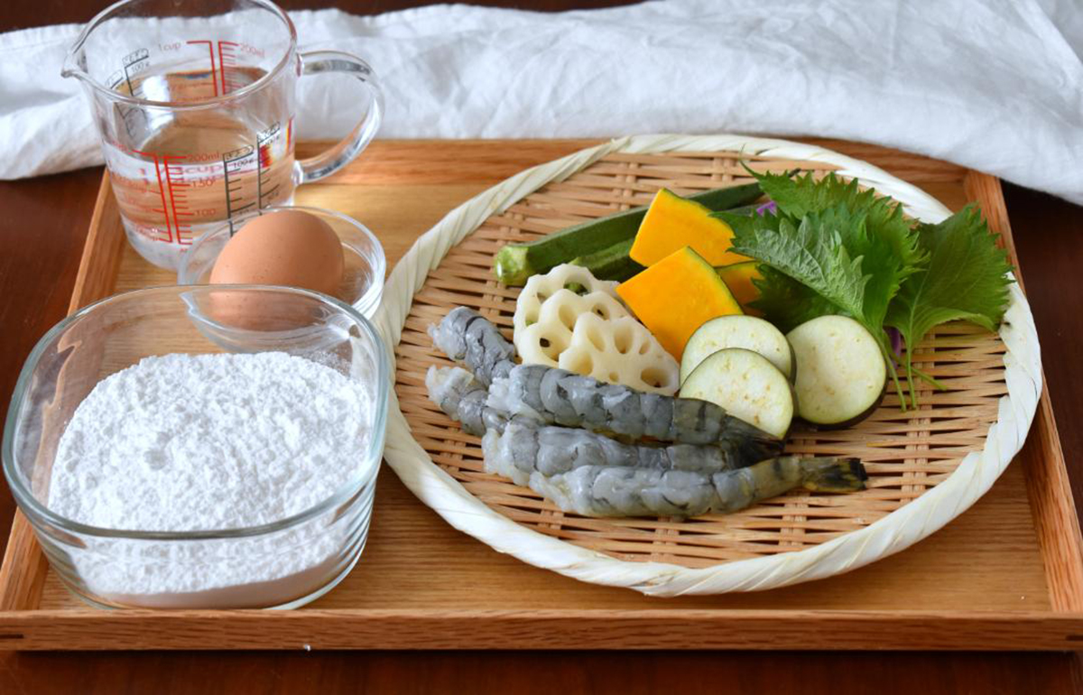 米粉と卵、水、ザルに食材が盛られた米粉天ぷらの材料